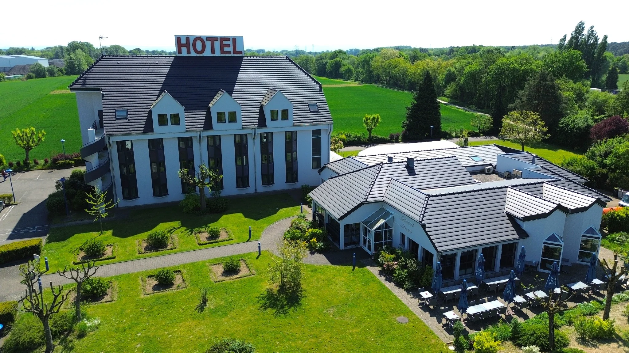 Vue aérienne de l’hôtel-restaurant La Tour Romaine, de sa toiture sombre et de ses façades rénovées